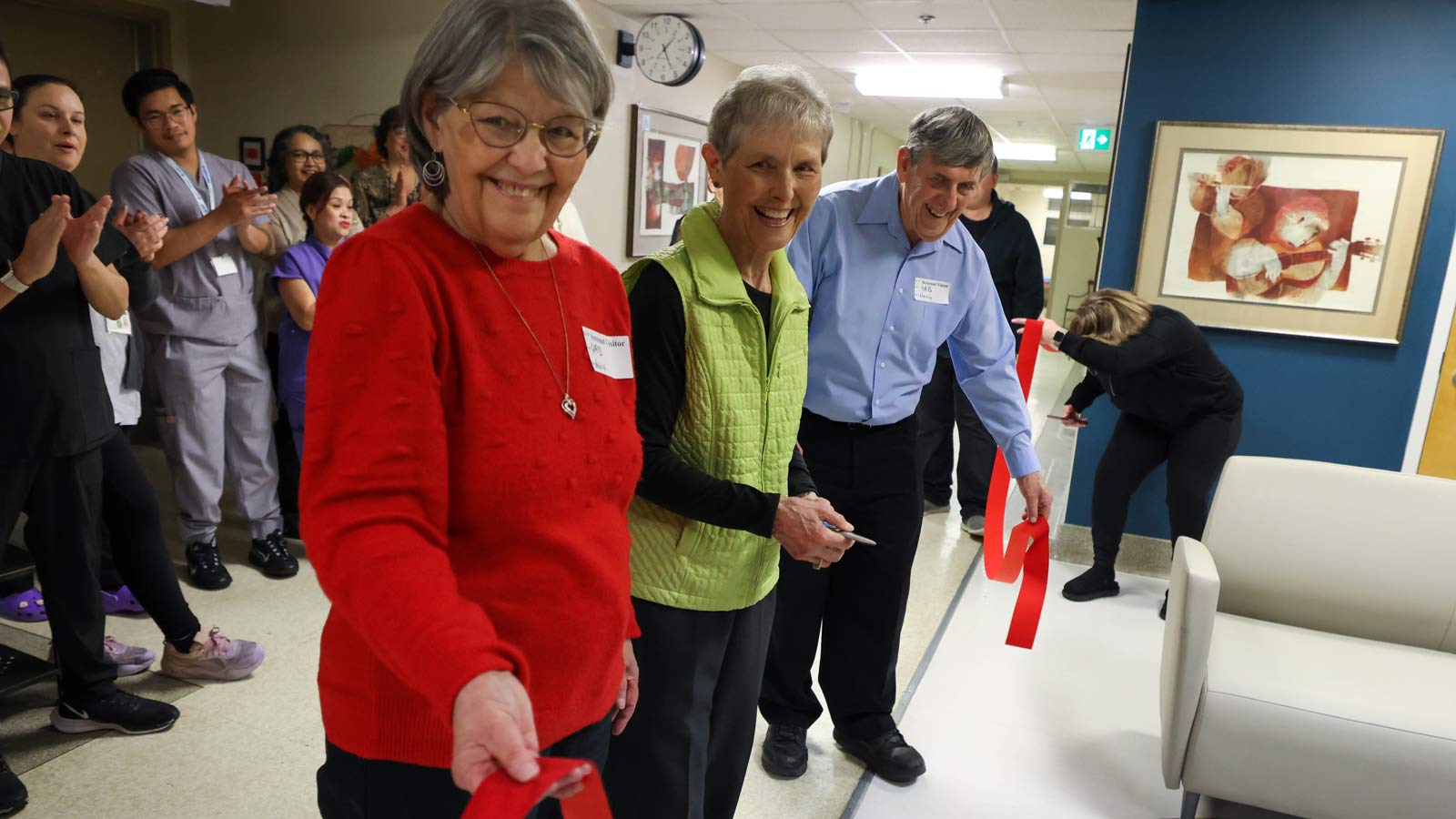 Seniors perform a ribbon cutting ceremony attended by healthcare workers