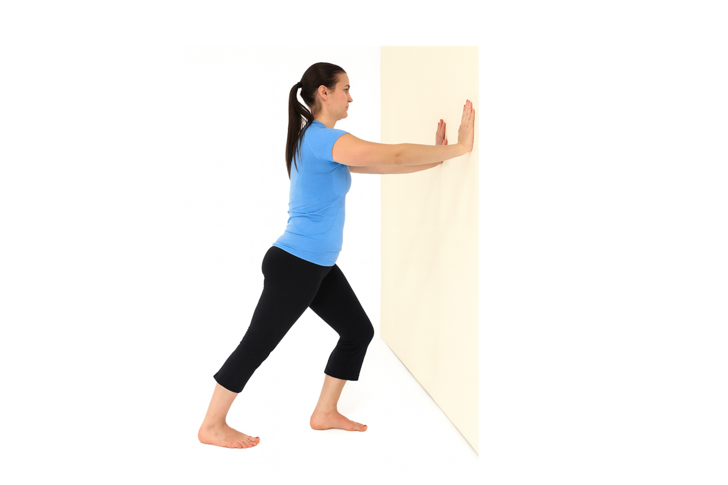 images of a woman in a blue shirt and black short demonstrating standing calf stretch on wall