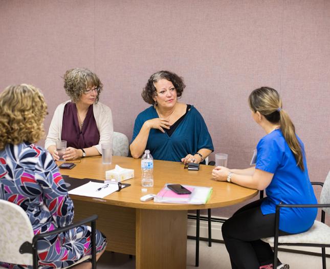 Four community board members meet at a boardroom table. 