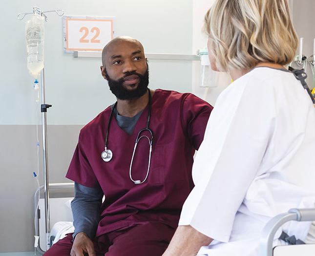 Staff member interacts with a patient in a hospital bed.