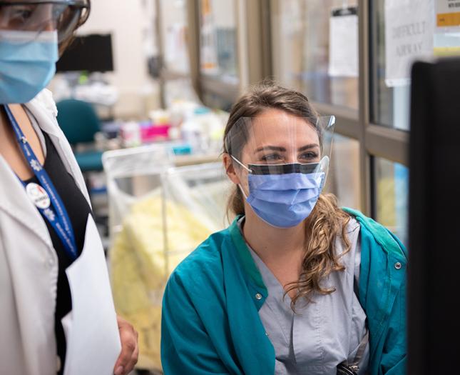 A Covenant Health student and mentor work at a computer.