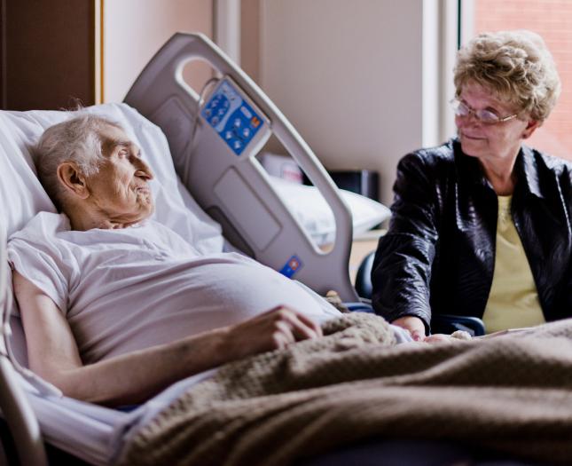 A family member sits at a loved one's bedside.