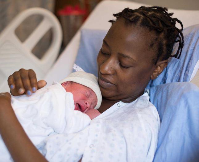 A mother cuddles a newborn against her chest.