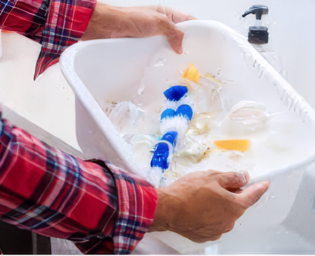 Hands holding a basin with soapy water and pump parts