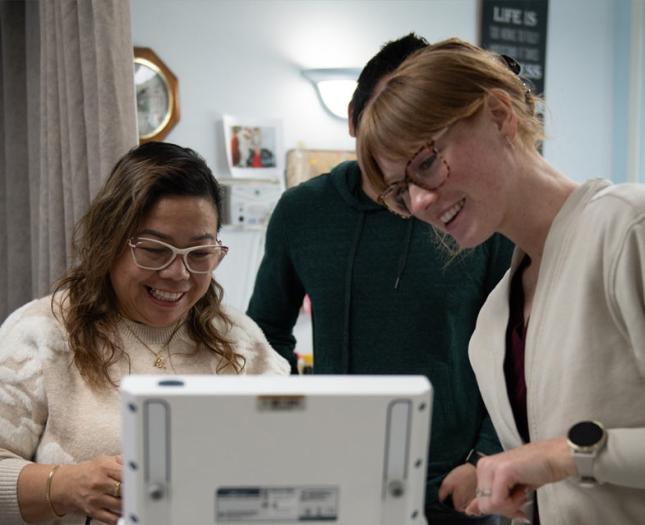 A young and old woman smile as they look at a monitor.
