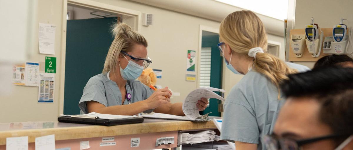 A registered nurse looks through paperwork with a colleague