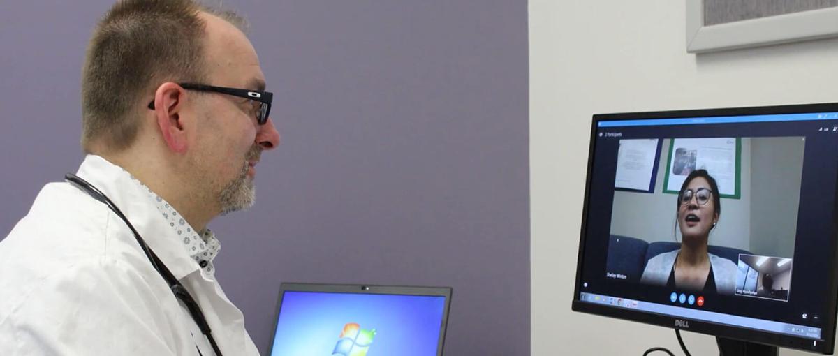 A doctor attends a virtual meeting on his computer