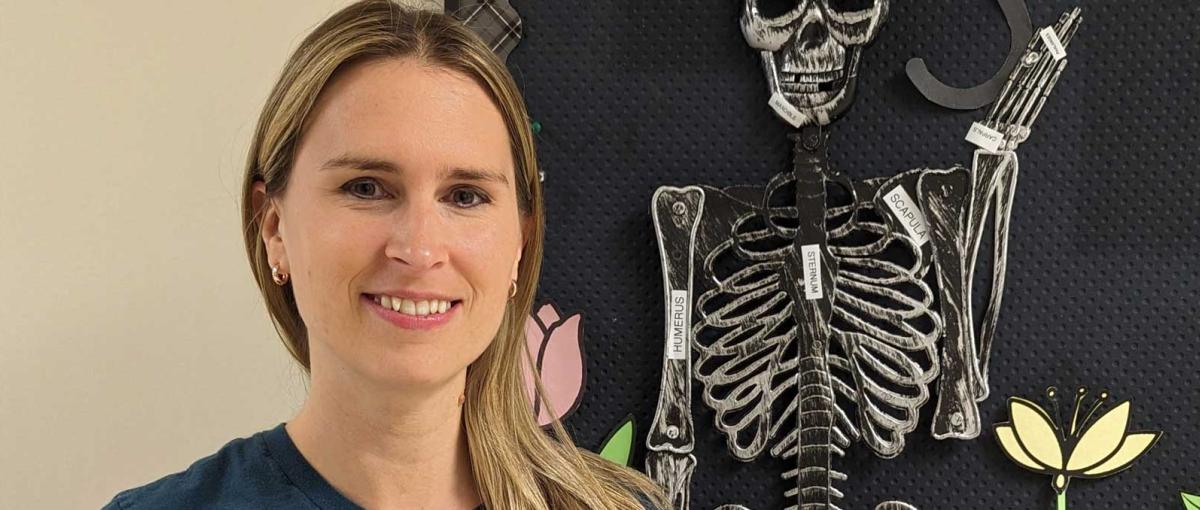 Holley Santos poses in front of a skeleton decoration