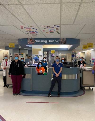 A healthcare team poses in front of nursing unit 52 at the Grey Nuns Community Hospital