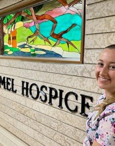 Christina poses near a stained glass window on Carmel Hospice.
