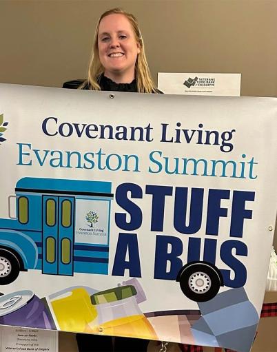 A woman holds up a sign for Evanston Summit's Stuff A Bus food drive