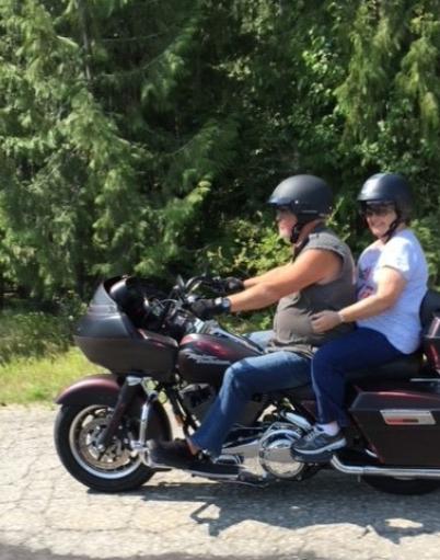 Joyce Morrison sits behind her son on a motorcycle during a sunny day