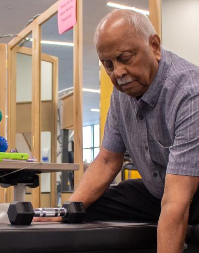 Man exercising with dumbbells while sitting on a bench in a fitness room