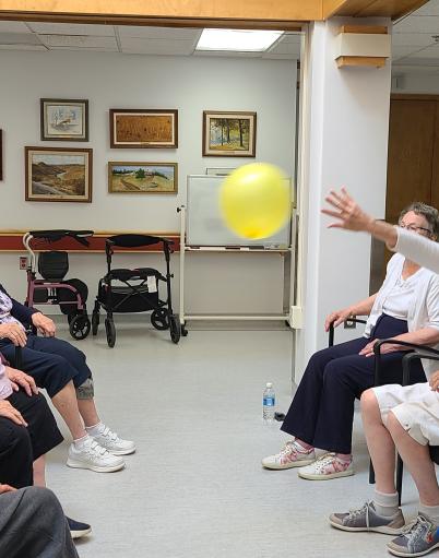 Seniors sitting together while keeping a balloon in the air.