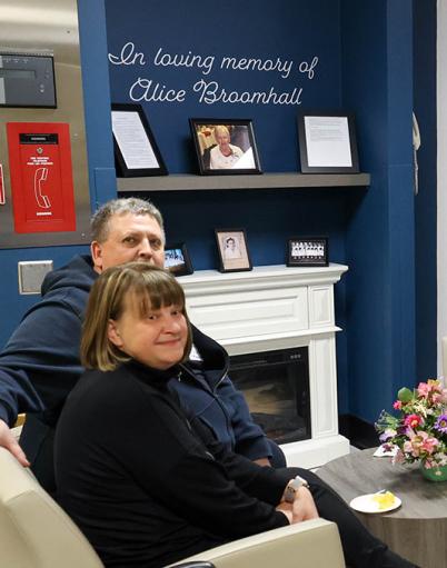 People sitting around a coffee table in front of photos and a dedication to Alice Broomhall