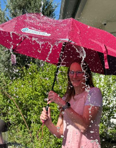 Lady under a red umbrella with water splashing the umbrella