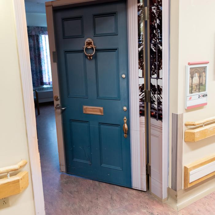 Teal door decorated to resemble a house entrance