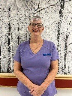 Lynn Williams Lynn poses in purple scrubs.