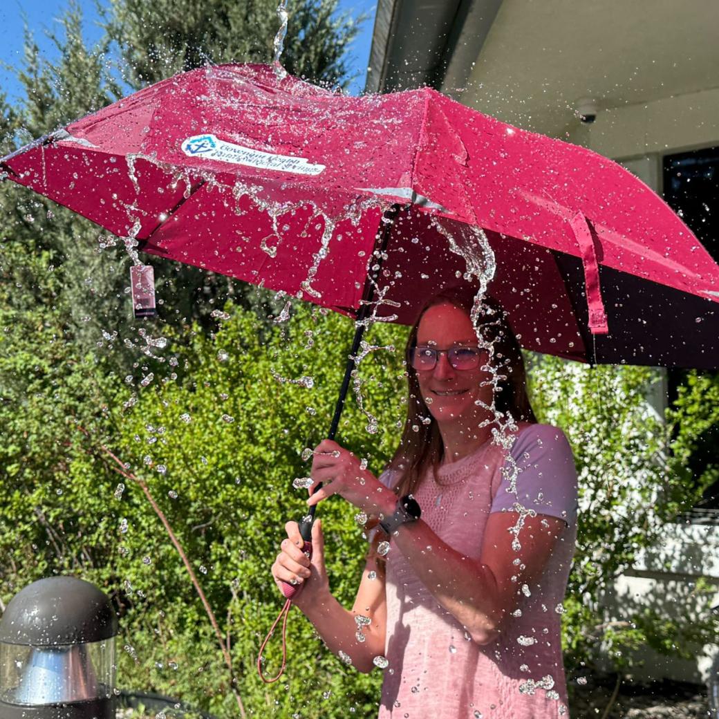 Lady under a red umbrella with water splashing the umbrella