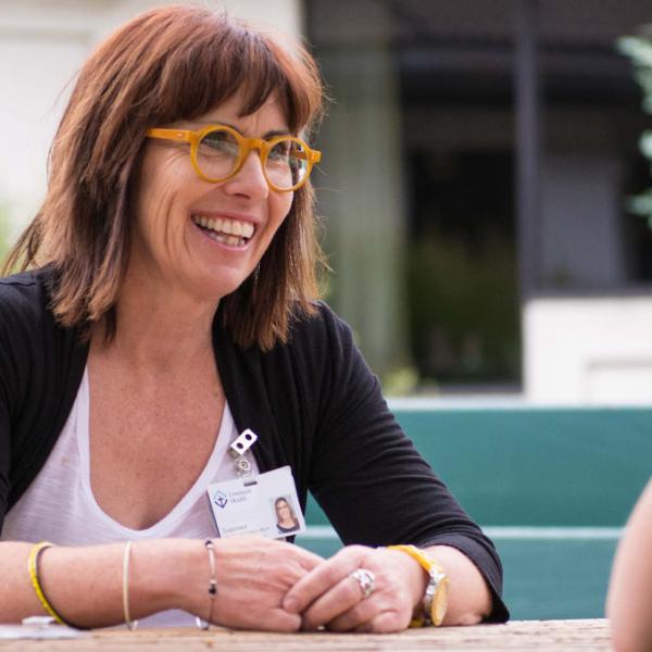 A smiling Covenant Health leader sits with an employee at an outside table