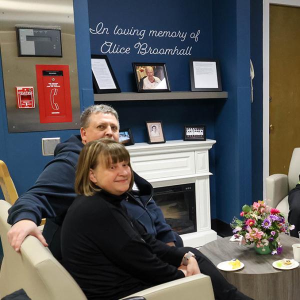 People sitting around a coffee table in front of photos and a dedication to Alice Broomhall