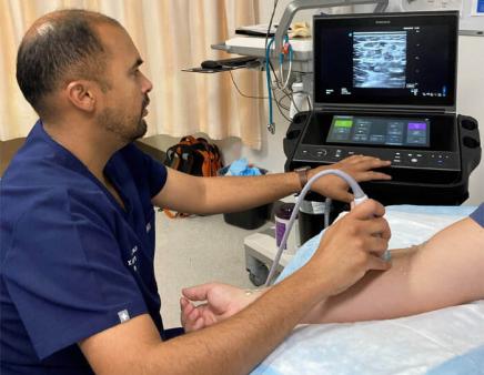 A doctor uses ultrasound vein mapping on a patient's arm to determine hemodialysis access for the patient