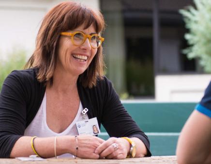 A smiling Covenant Health leader sits with an employee at an outside table